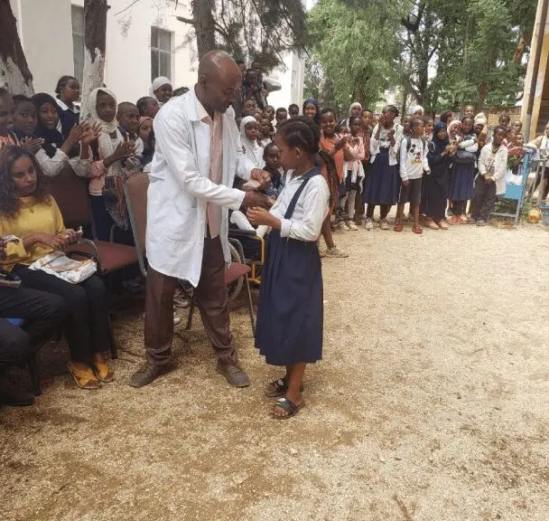 A man and woman shaking hands in front of a crowd.