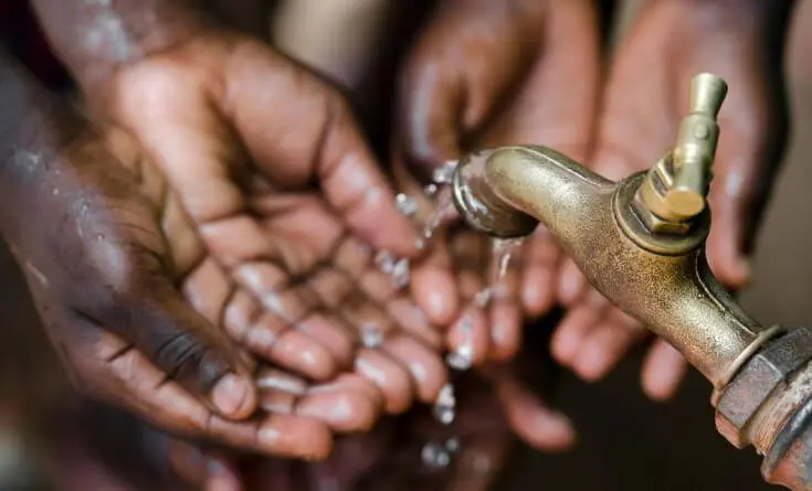 A person is drinking water from a faucet.