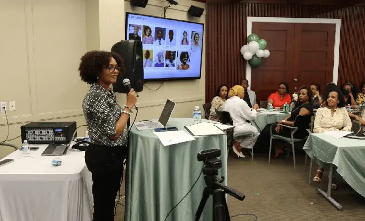 A woman standing at a table with a microphone.