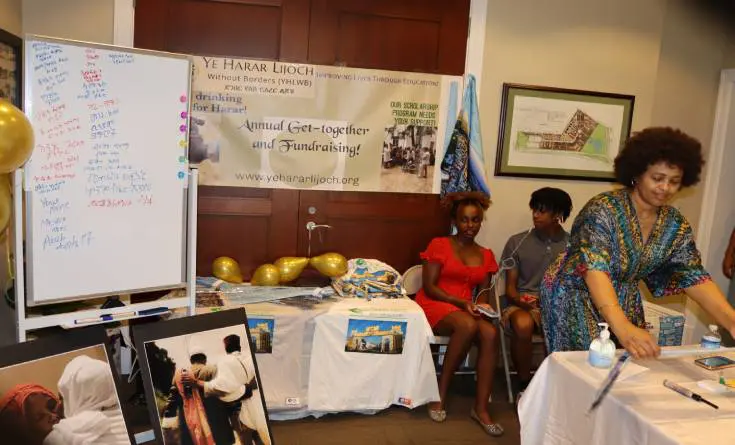 Two women sitting in front of a table with posters.